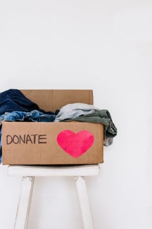 A box on a chair full of clothes to be donated.