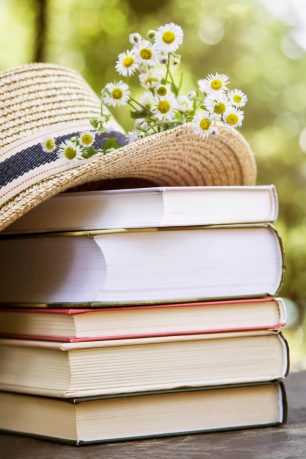 A stack of books with a hat sitting on top.