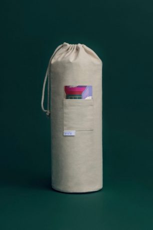 Image of Henrie pillow in canvas packaging over an emerald green backdrop